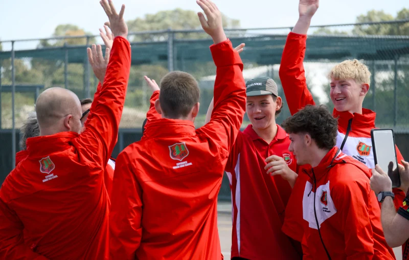 A group of students & staff cheering with arm in the air.