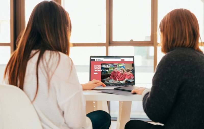 Two women sitting at a table looking at the new Esperance Senior High School Website on a laptop