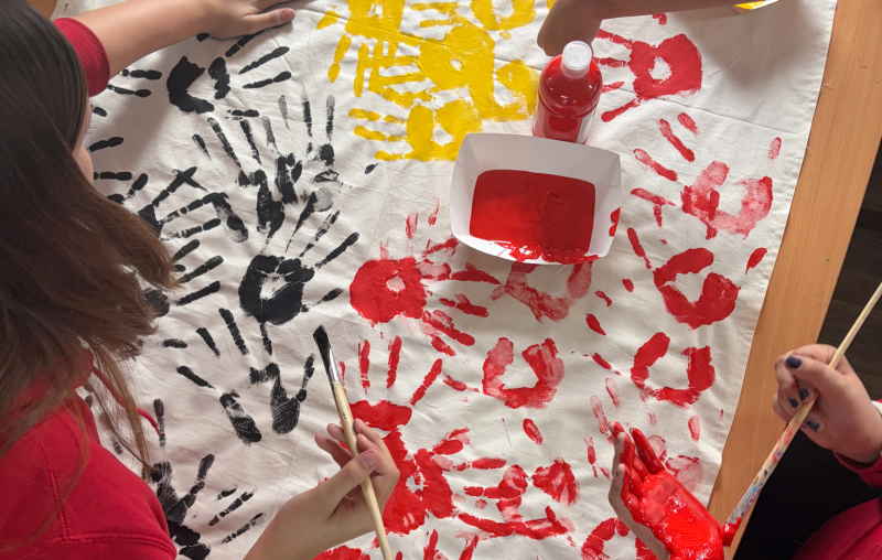 Top down image of students hand panting that resembles the Aboriginal Flag